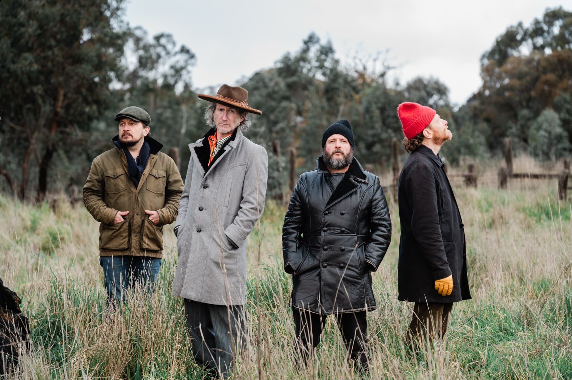 The cast of 'Waiting for Godot' standing in a grassy paddock at Castlemaine, looking in different directions. Photo by penny ryan photography.