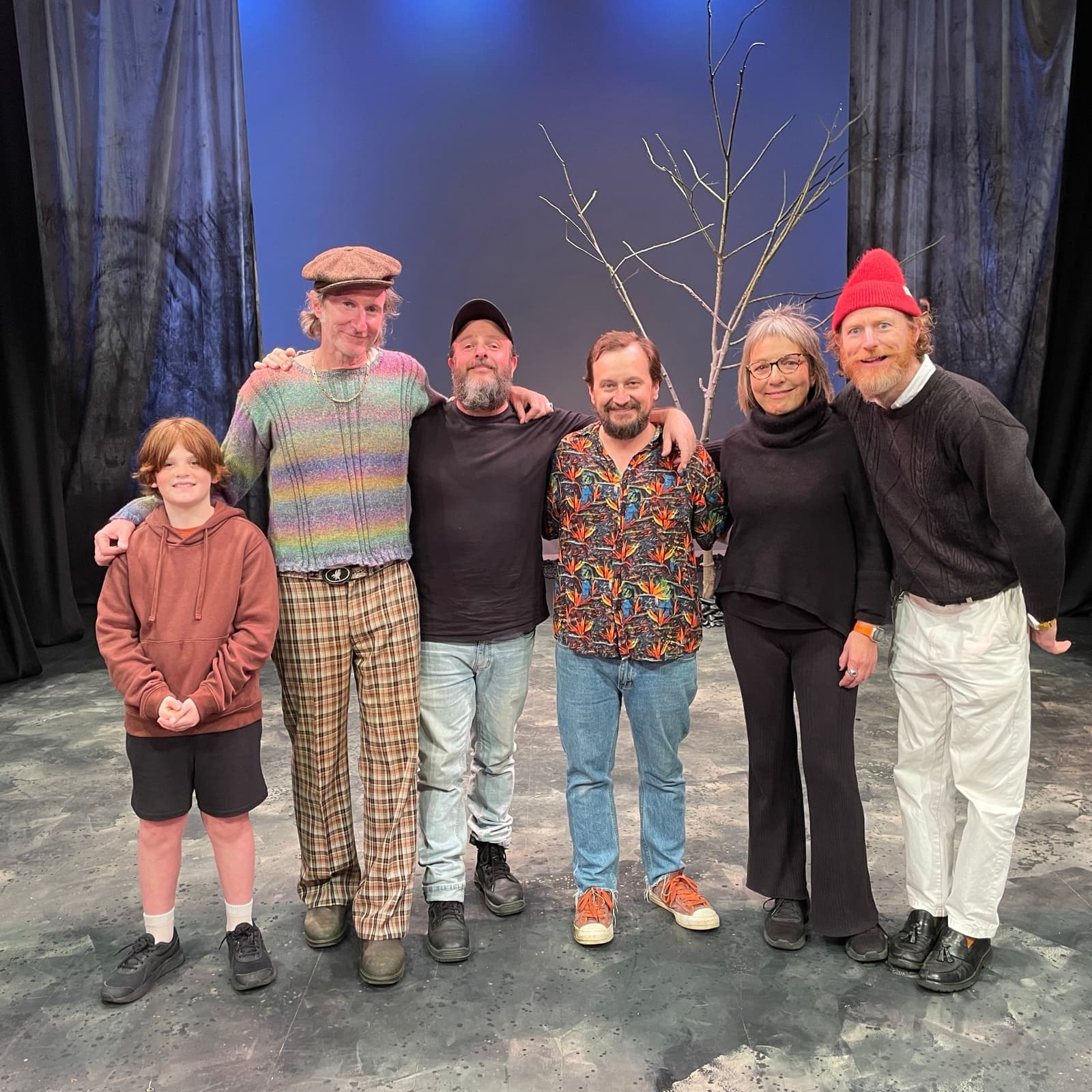 The cast and director of Waiting for Godot stand together on the set beneath the bare tree