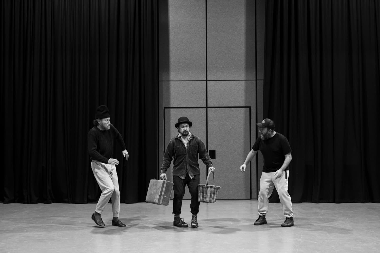 Lucky arrives with suitcase and basket, watched by Vladimir and Estragon